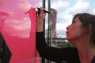 Une femme dessine sur un mur rose